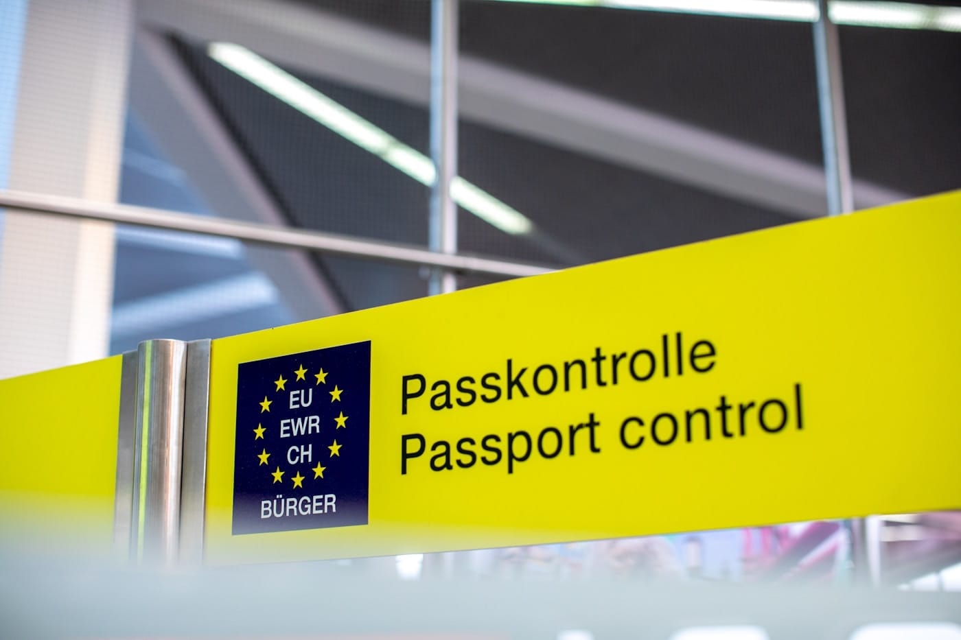 A yellow airport sign reading Passkontrolle / Passport control, a metaphor for a DNS query that gets a different outcome depending on which booth answers it