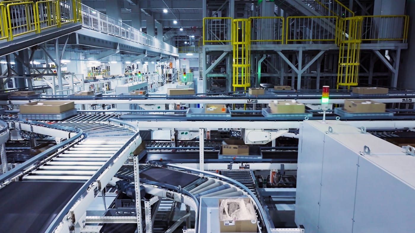 An automated warehouse sorting facility with conveyor belts carrying boxes, a metaphor for a blockchain-native name still routing through one ordinary, centralized hub