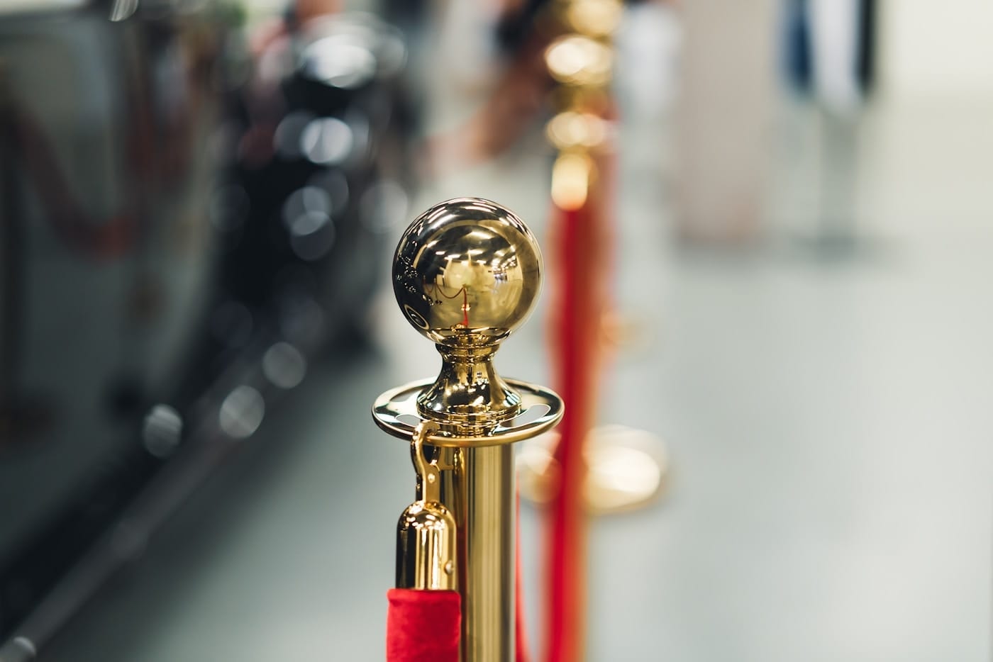 A brass stanchion and red velvet rope barrier, a metaphor for a bot-mitigation challenge that gates a request after DNS has already answered