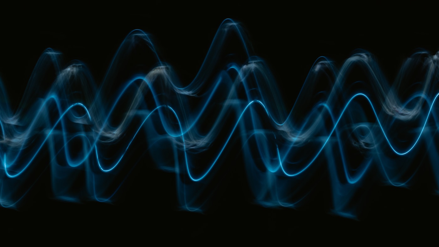 A luminous blue waveform against black, a metaphor for an audio-native model classifying an acoustic signature with no words involved