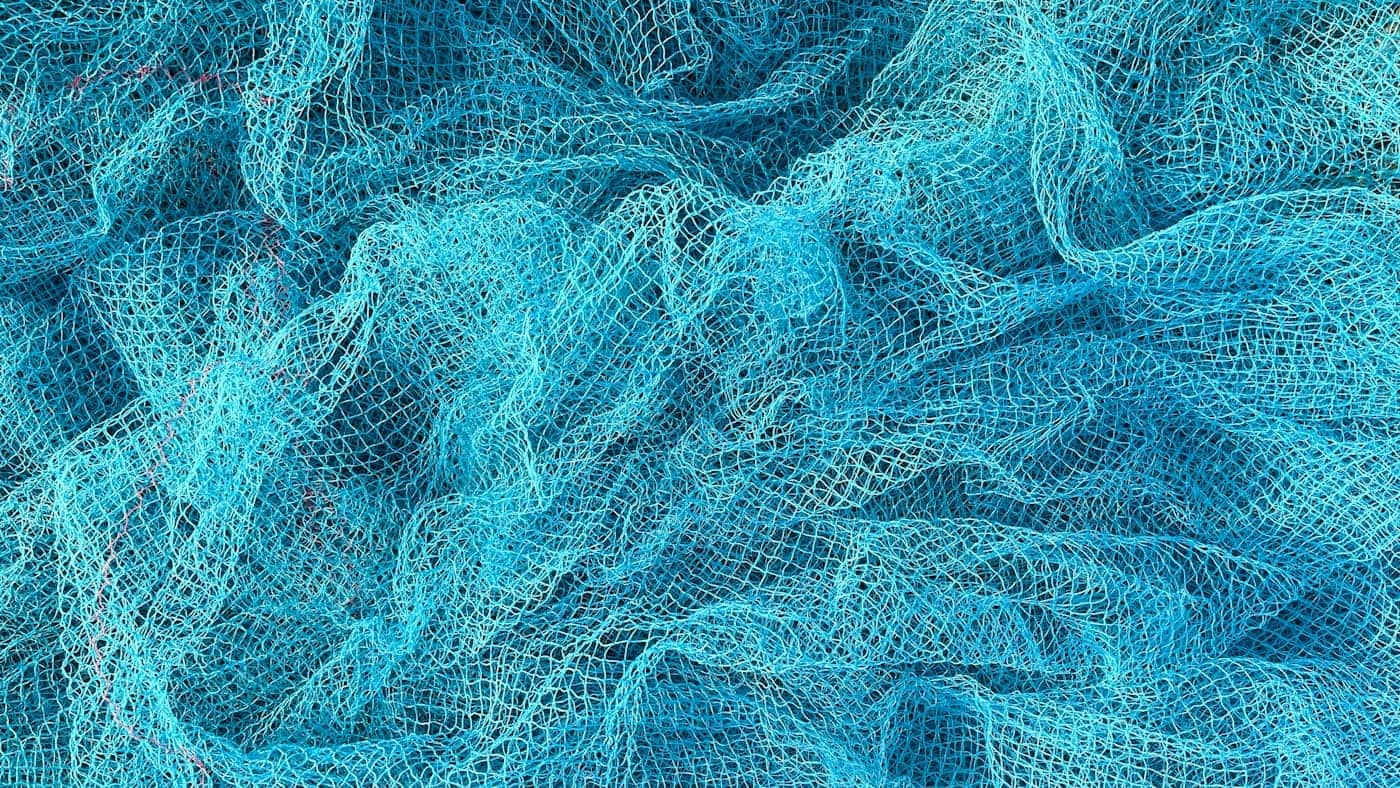 Close-up of a woven blue fishing net, a metaphor for a two-tower model where a user vector and an item vector meet through a single connection
