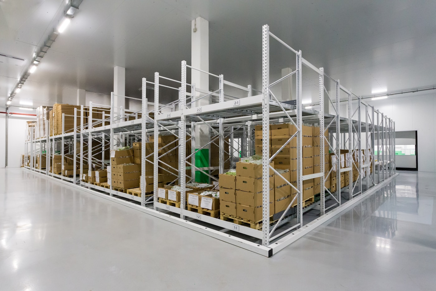 A partially assembled white metal shelving frame standing alone on an empty floor