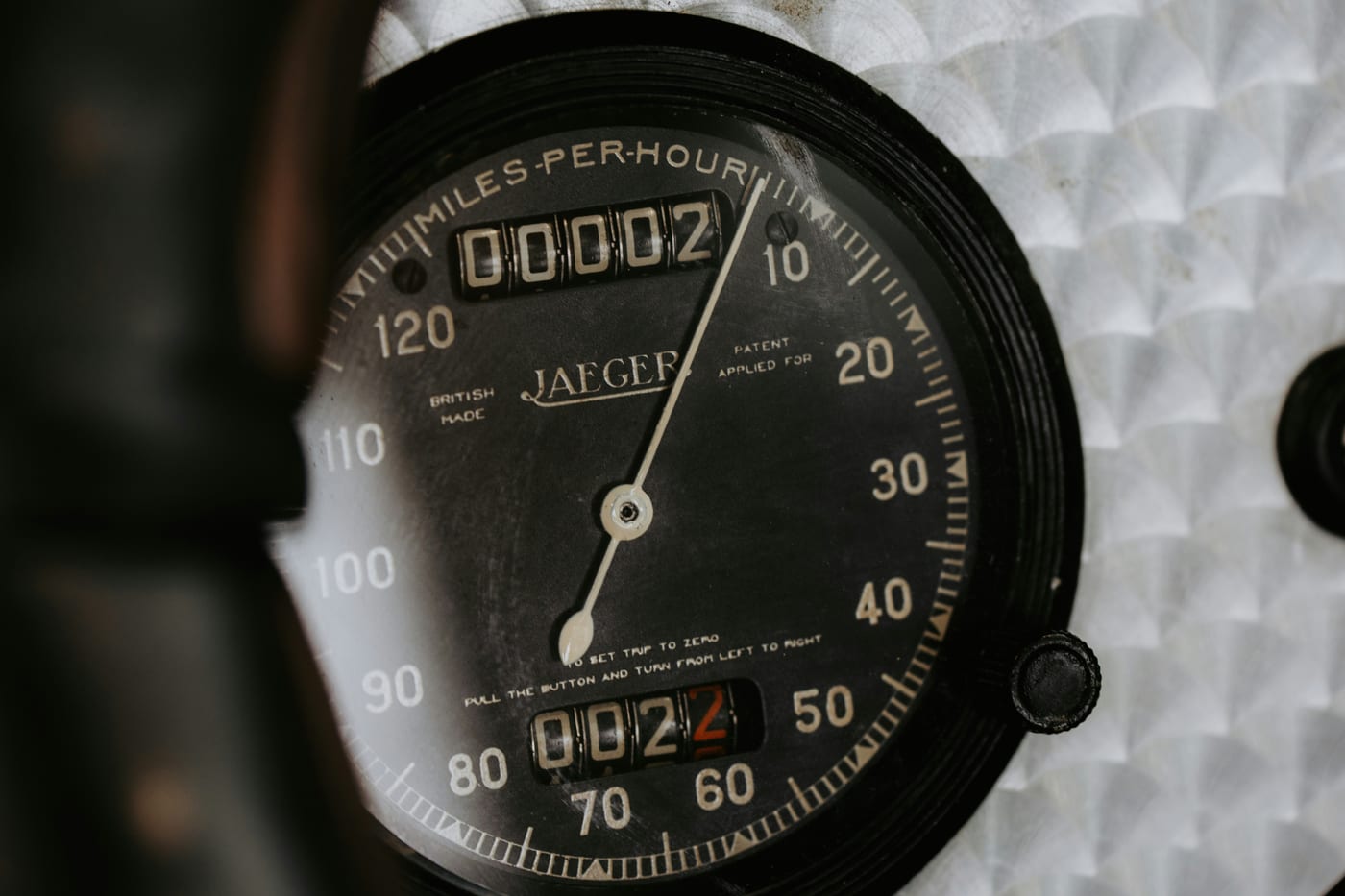 A vintage Jaeger speedometer needle resting near zero, the odometer wheels barely past 00002, a metaphor for an instrument reporting zero because that is the smallest value its resolution allows