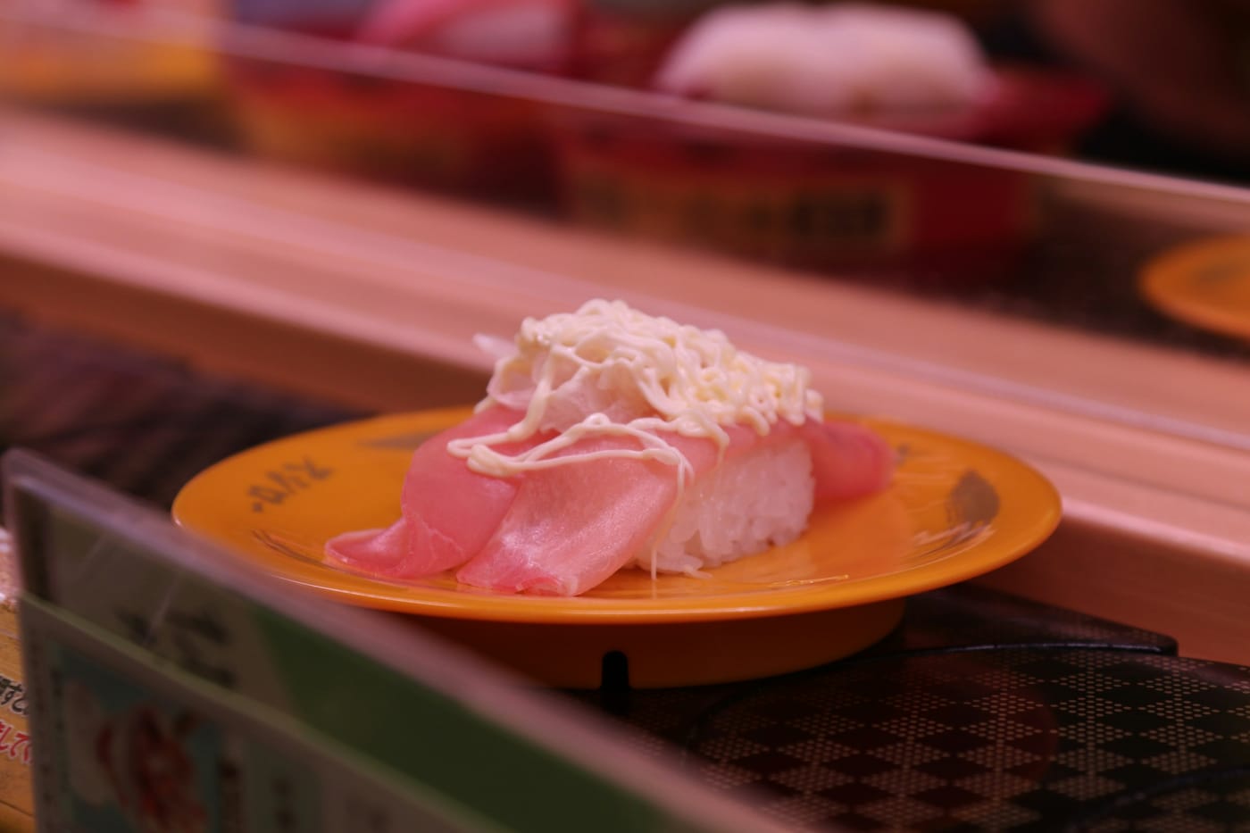 A plate of sushi riding a conveyor belt past an empty stretch of counter, a metaphor for a producer that keeps its own pace whether or not anyone takes the plate