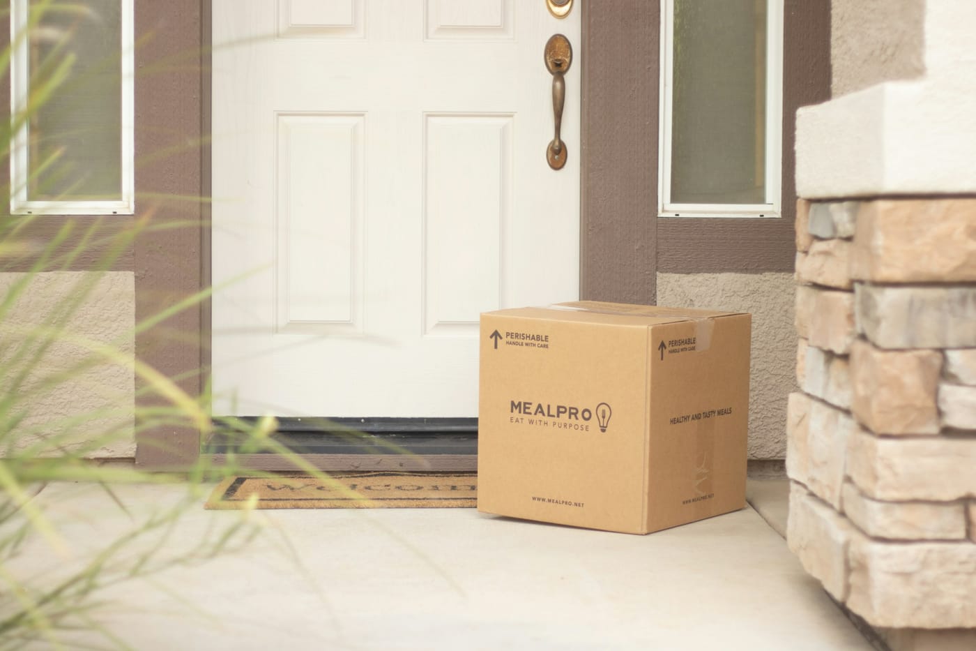 A cardboard meal-delivery box left on a doorstep in front of a closed front door, a metaphor for tokens that were produced and delivered but never read