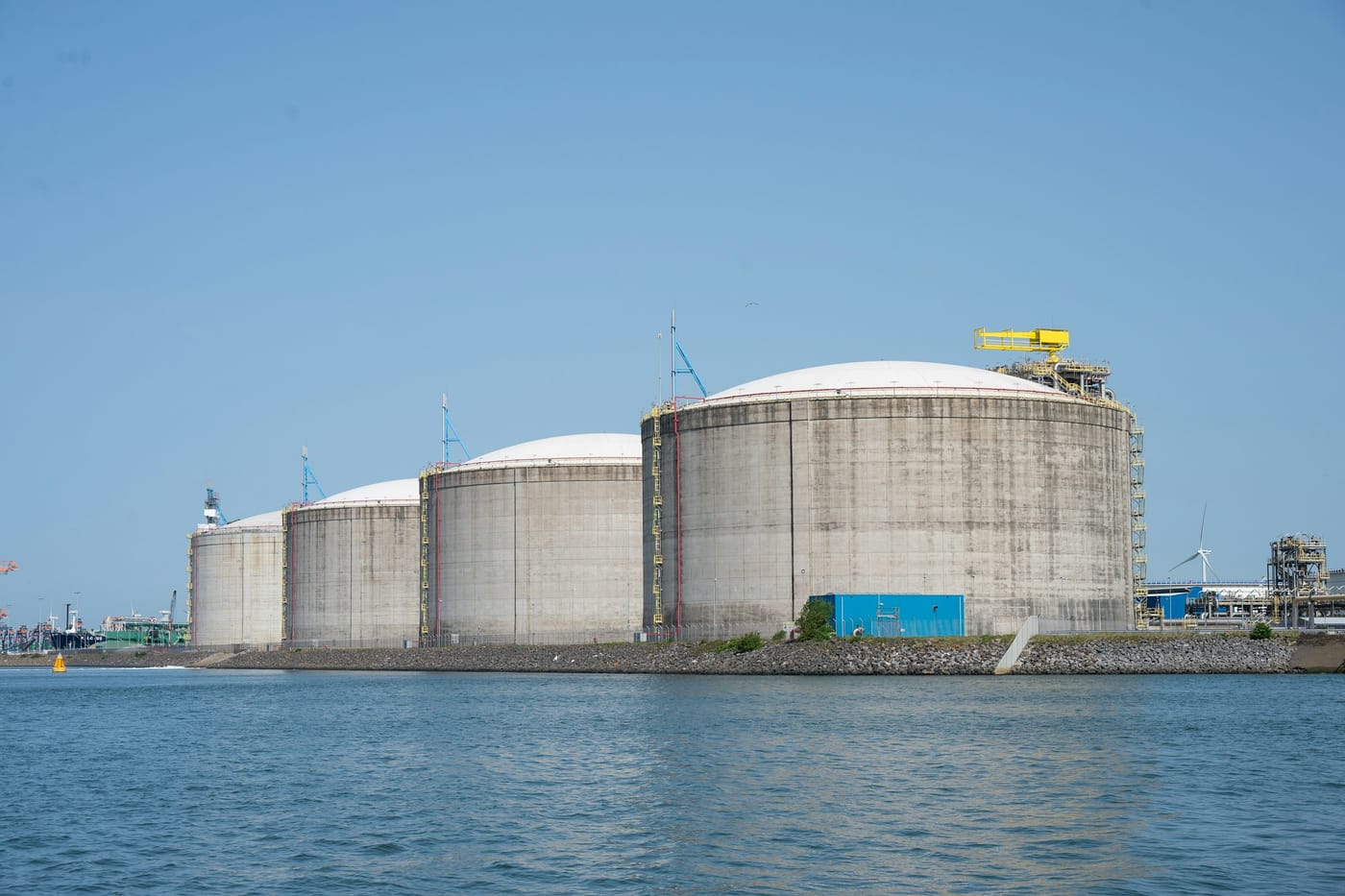 A row of large concrete storage tanks standing along the edge of a harbour, a metaphor for the buffers that sit between the producer and the reader