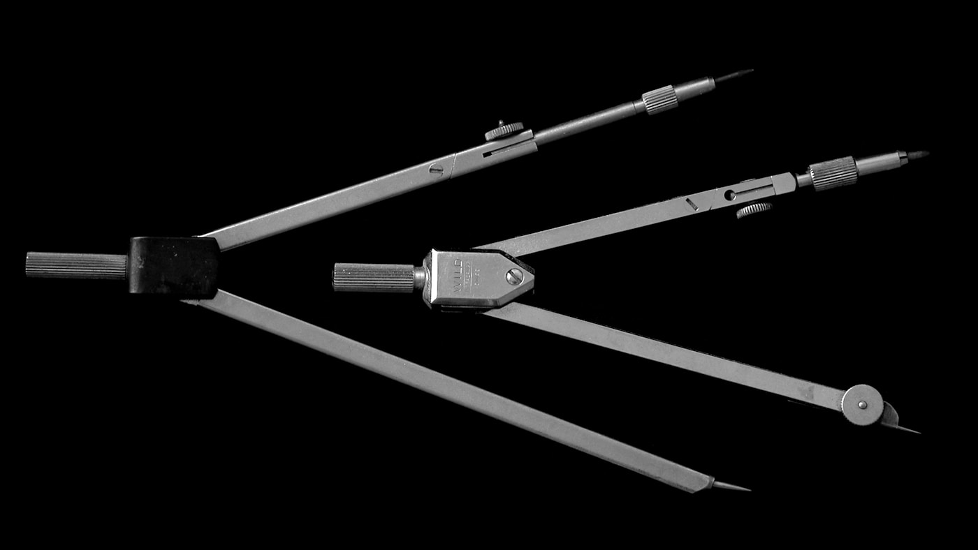 Two precision drafting compasses on black, the kind of instrument that draws a coordinate system before anything gets measured against it