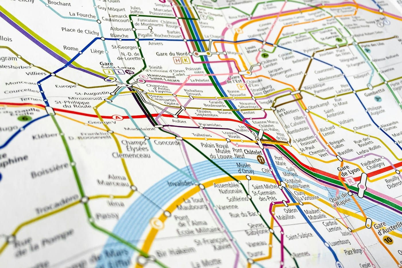 A close-up of a Paris Metro map, colored transit lines connecting circular station nodes