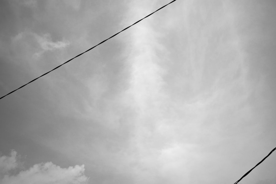Two thin wires crossing an empty overcast sky, a metaphor for a margin with nothing underneath it